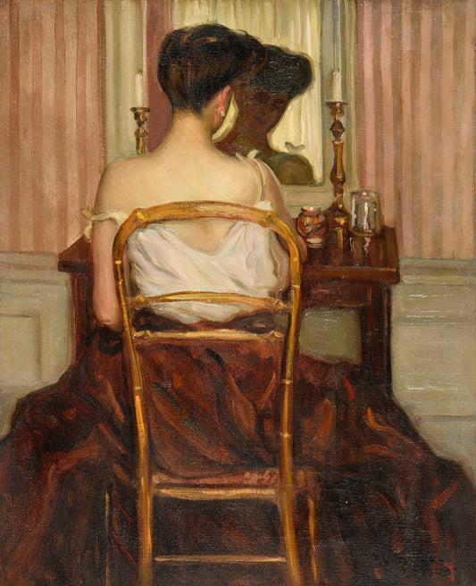 A woman seated at her dressing table in a vintage interior, wearing a white blouse and brown skirt, reflecting softly in the mirror – Devant la Glace (1903) wall art reproduction.
